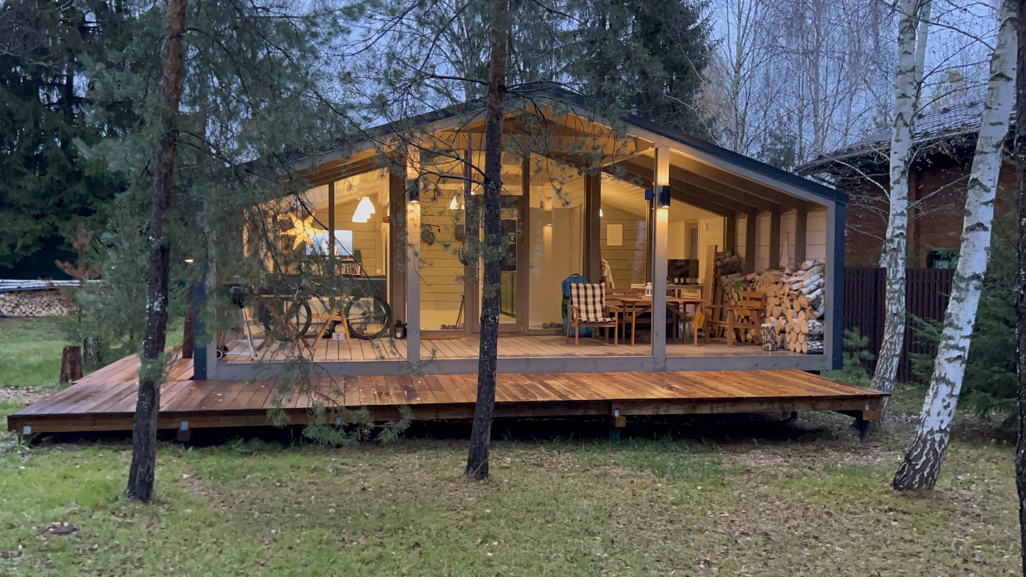 Дом с панорамными окнами и верандой в хвойном лесу